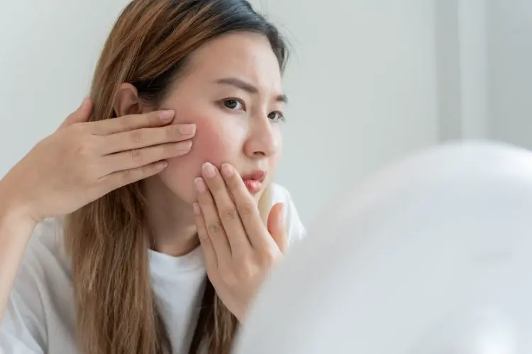 Une femme regarde ses problèmes de peau dans un miroir