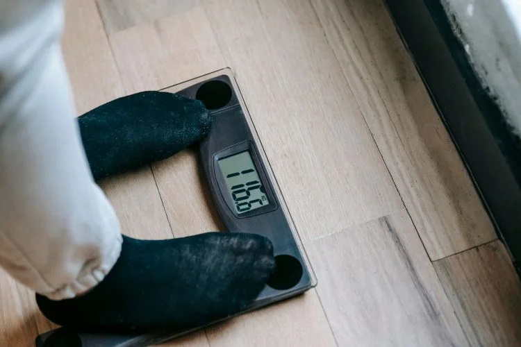 Une personne pesant 116 kg qui se pèse sur une balance transparente.