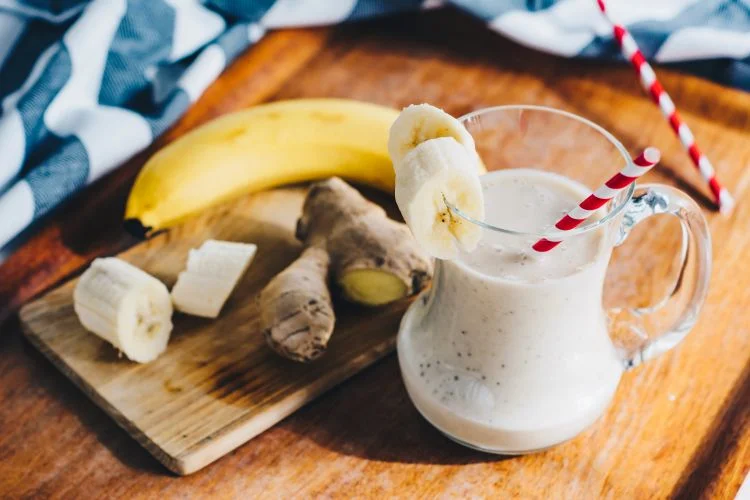 Un smoothie banane-gingembre servi sur un plateau en bois.