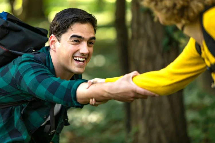 Un randonneur qui se fait aider par sa sœur en pleine forêt
