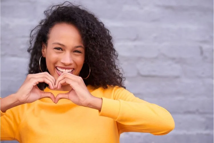 Une femme heureuse qui fait un signe de cœur avec ses mains